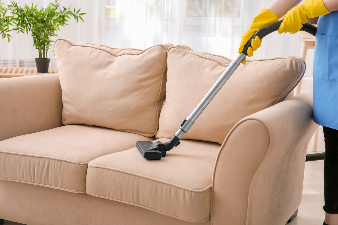 Woman Cleaning a Sofa with Vacuum Cleaner 